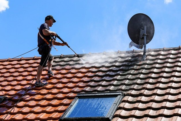 Elite Roofing Noosa technician pressure washing a tile roof to remove dirt and debris